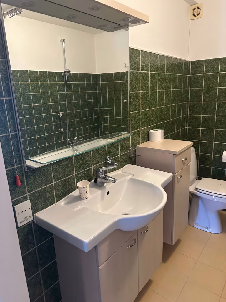 Verouderde badkamer met donkergroene tegels en een standaard ligbad in Alphen aan den Rijn.