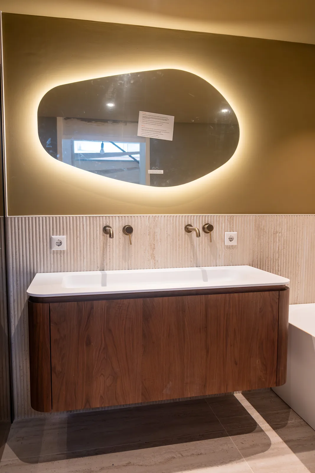 Sfeervolle luxe badkamer in Alphen aan den Rijn met vrijstaand bad, notenhouten wastafelmeubel en gouden kranen